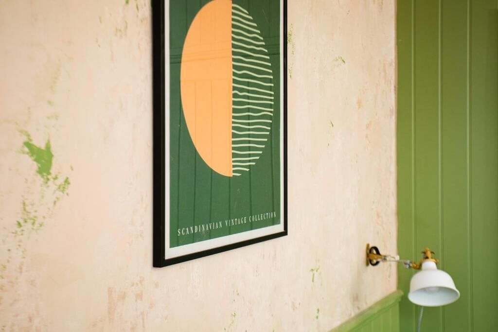 Coleção de arte vintage escandinava emoldurada numa parede, com uma porta verde e uma luminária fixada.