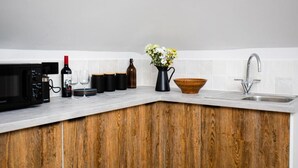 A kitchen with a microwave, wine bottle, glasses, and a wooden bowl. - Settle Southampton (Southampton)