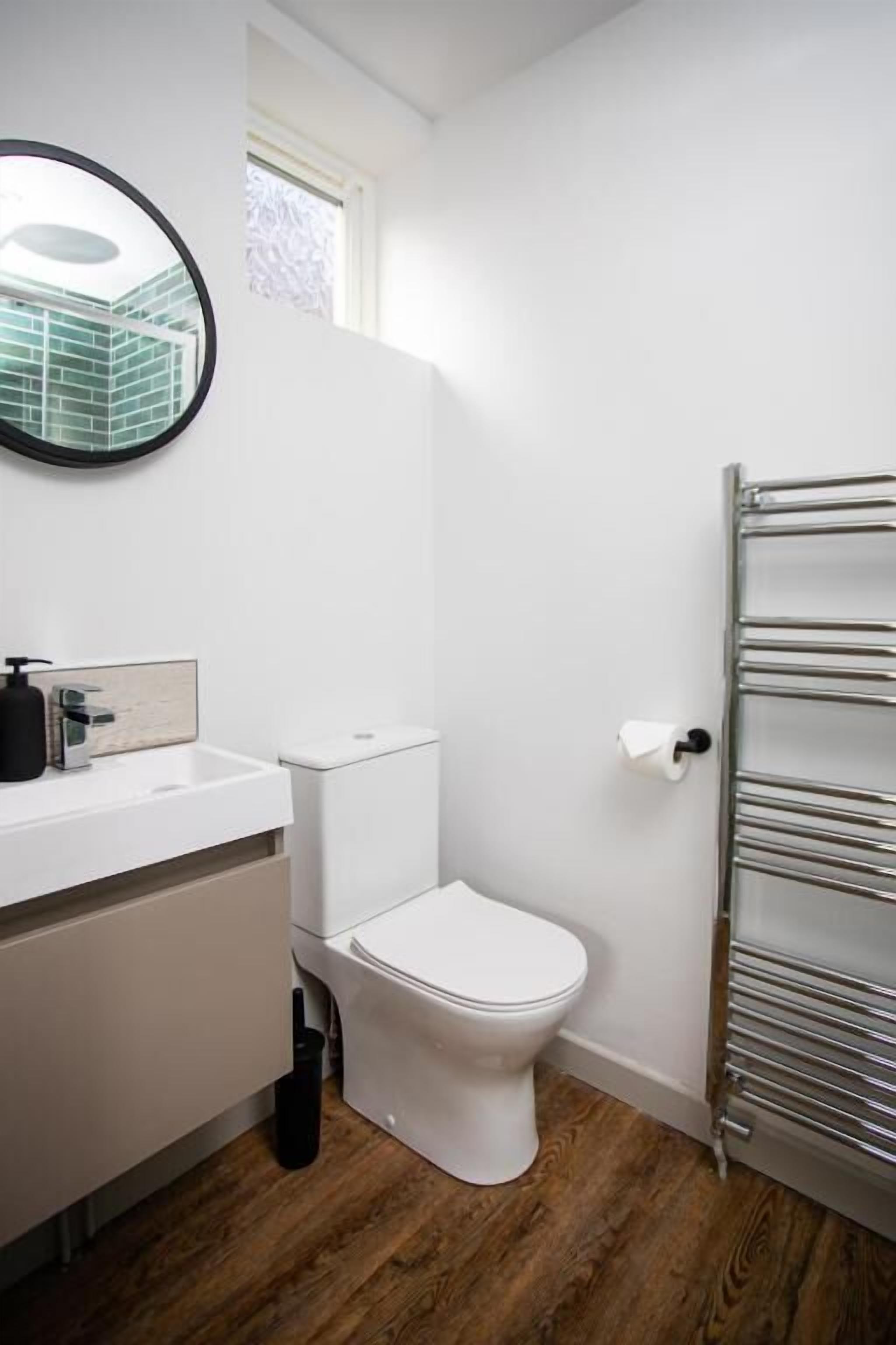 Un bagno con un lavandino bianco, uno specchio, un water e un portaserviti.