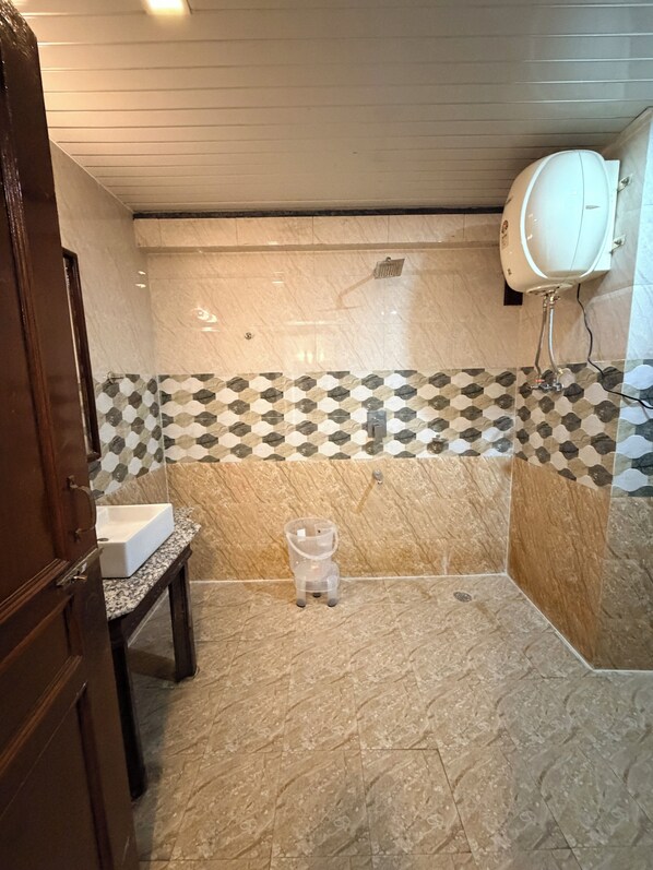 Un baño con piso de mármol, lavamanos, inodoro y zona de ducha.
