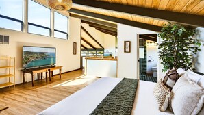 Un dormitorio con una cama grande, suelo de madera, televisión y vistas al exterior.