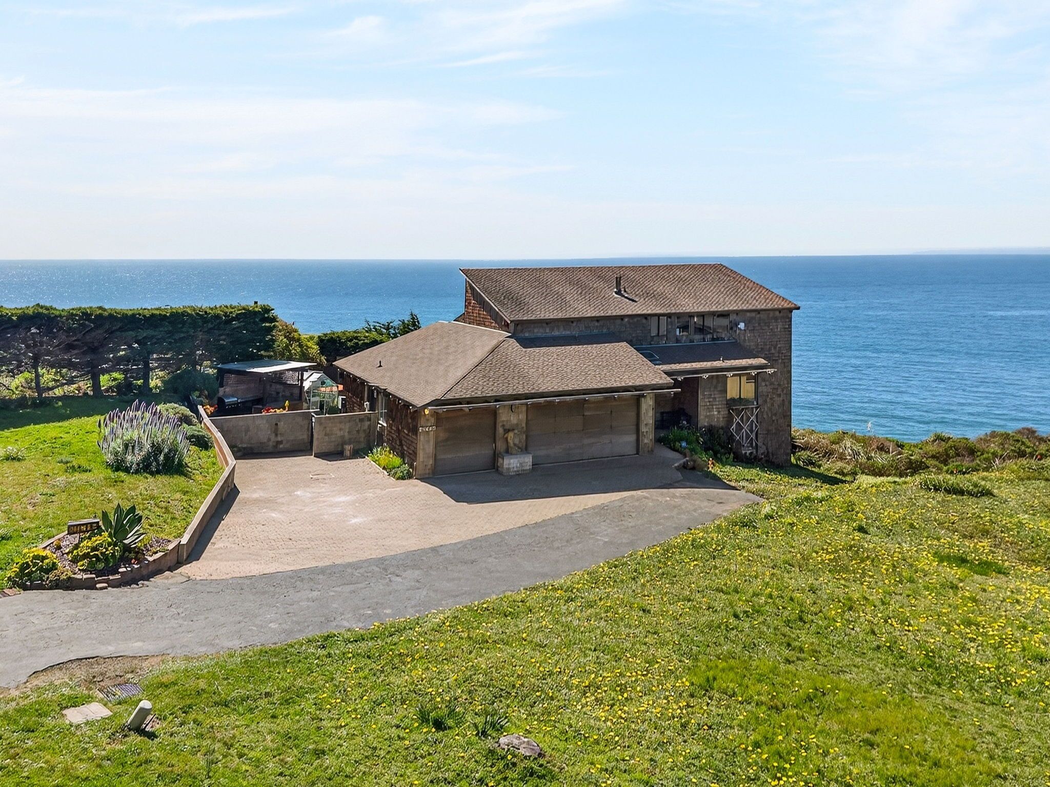 A two-story house with a garage, a driveway, and a view of the sea.