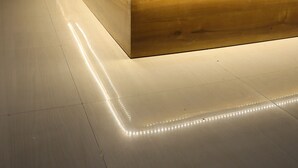 Una cama moderna con estructura de madera, ropa de cama blanca y cabecera con espejo.