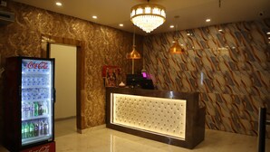 Un área de recepción con pared de mármol, un refrigerador de Coca-Cola y un mostrador de recepción con tapizado.
