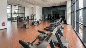 A gym with exercise equipment, large windows, and a fire extinguisher on the wall. - Chambers Residence by Airhost (Kuala Lumpur)