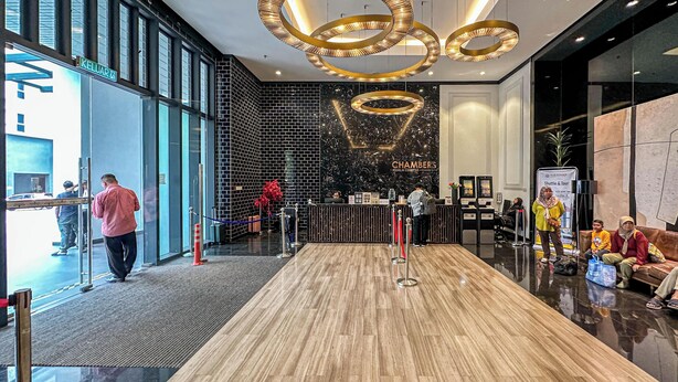 A hotel lobby with a reception desk, a black wall with a chandelier, and a wooden floor. - Chambers Residence by Airhost (Kuala Lumpur)