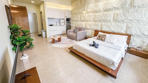 A modern bedroom with a large bed, a seating area, and a kitchenette. - Chambers Residence by Airhost (Kuala Lumpur)