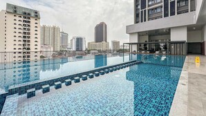 A rooftop swimming pool with tiled flooring, surrounded by high-rise buildings. - Chambers Residence by Airhost (Kuala Lumpur)