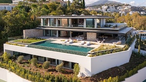 A modern house with a rooftop pool, large windows, and a view of a cityscape.