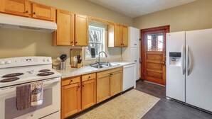 A kitchen with wooden cabinets, a white stove, a sink, and a refrigerator. - Ohio Valley Home Near Franciscan University! (Steubenville)