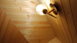 Een houten plafond met een lamp en een raam met gordijnen.