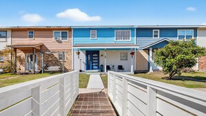A row of townhouses with a central entrance, a covered walkway, and a small garden area. - 1/2 Mi to Sylvan Beach Park! Chic Townhome w/ Yard (La Porte)