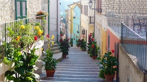 A narrow street with steps leading to a building, potted plants, and a metal railing. - Apartment with balcony and parking space (Numana)