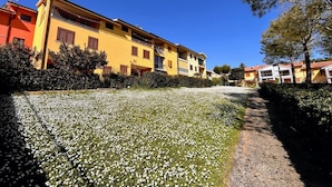 A residential area with colorful buildings, a pathway, and a field of white flowers. - Apartment with balcony and parking space (Numana)