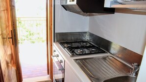 A kitchen with a gas stove, a sink, and a sliding door leading to a balcony. - Apartment with balcony and parking space (Numana)