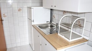 A kitchen with a stainless steel sink, white cabinets, and a wooden countertop.