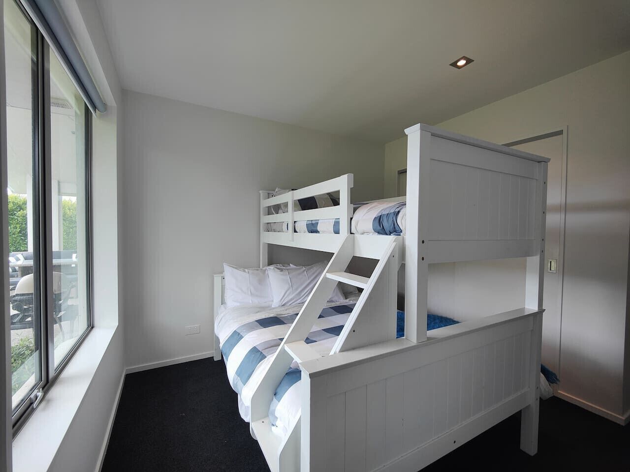 A bunk bed with a window, a door, and a light fixture.