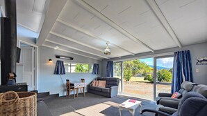 A cozy living room with a sofa, chairs, a table, and a fireplace. - Blue Bach in the Loop (Te Anau)
