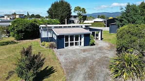 A residential property with a large house, a garage, and a covered outdoor area. - Blue Bach in the Loop (Te Anau)