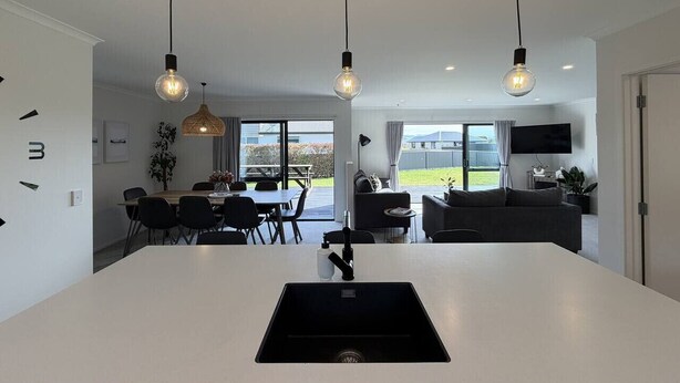 Une cuisine moderne dotée d’un îlot central, de luminaires suspendus et d’un coin repas avec une table et des chaises.