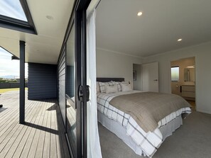 A bedroom with a large bed, a sliding glass door to a balcony, and a walk-in closet.