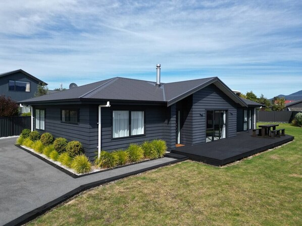 A modern two-story house with a dark exterior, a flat roof, and a small front porch.