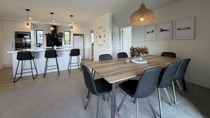 Une cuisine moderne avec des meubles blancs, un îlot central et des luminaires suspendus.