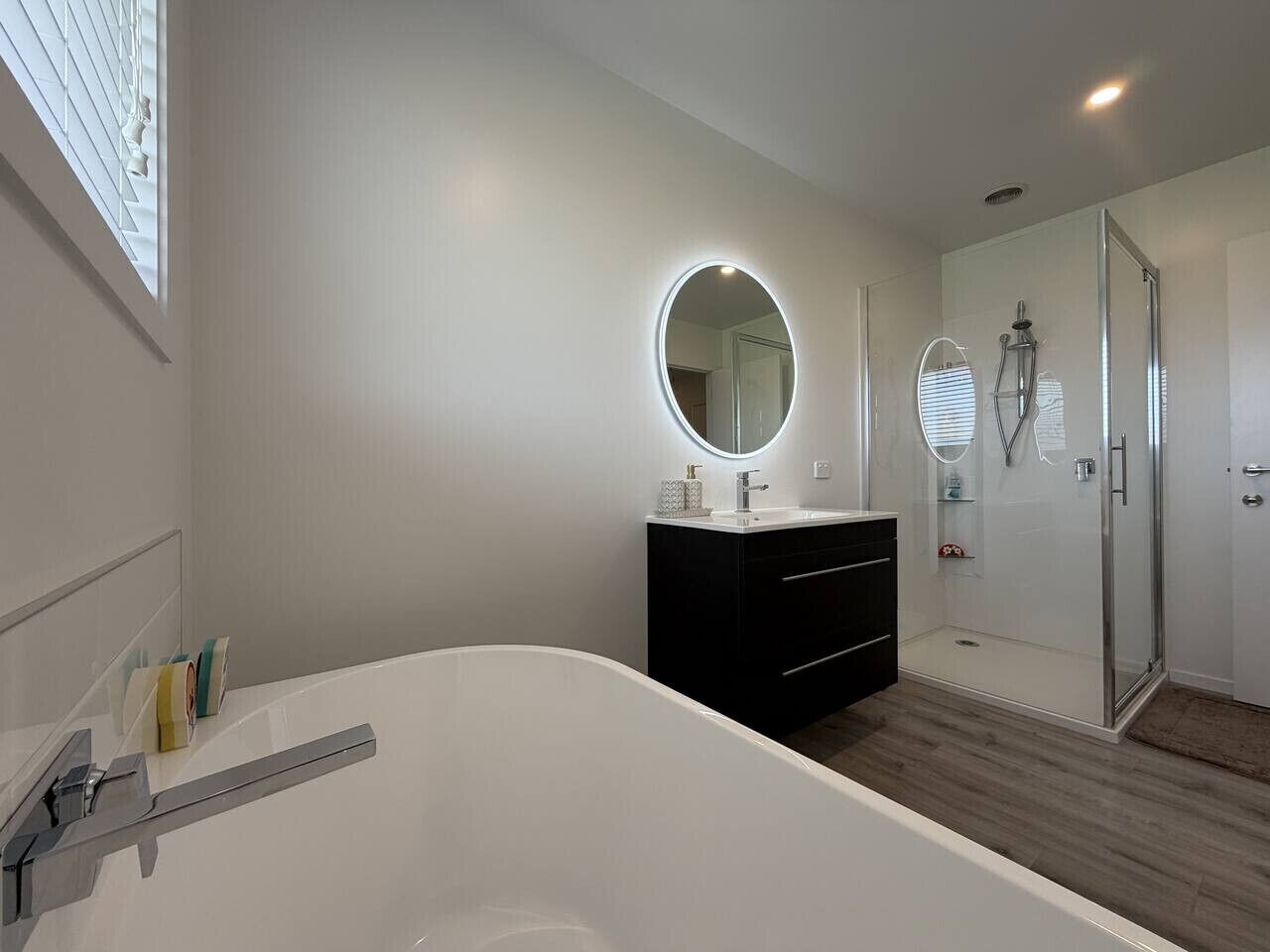 Een moderne badkamer met een vrijstaand bad, een wastafel met spiegel en een douchecabine met glazen wanden.