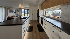 A modern kitchen with a central island, wooden cabinets, and a view of the outside.