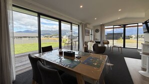 A spacious room with a large dining table, chairs, a sofa, and a TV.