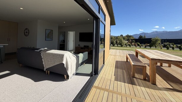 A modern house with a large sliding glass door leading to a deck.