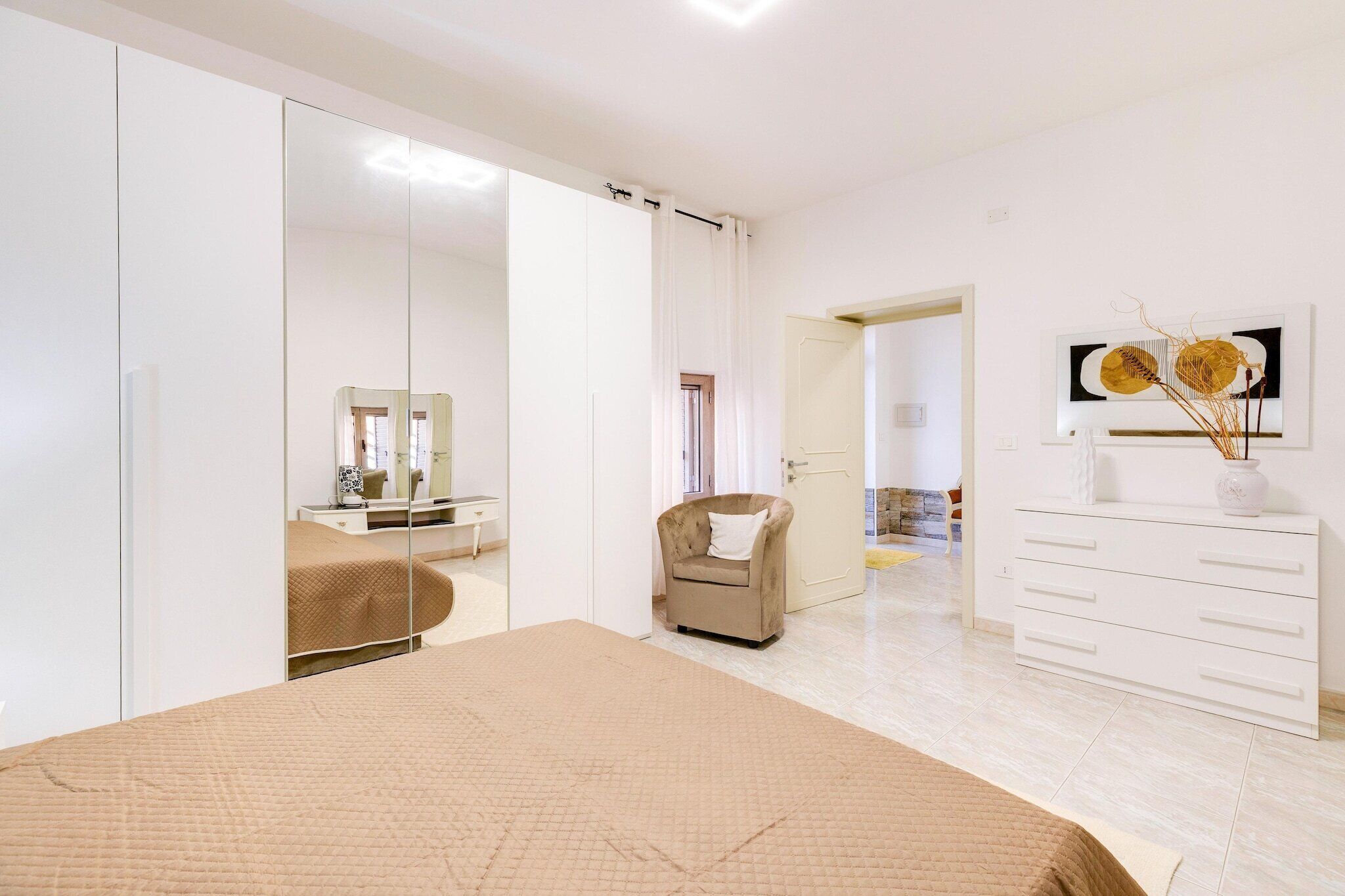A bedroom with a bed, a wardrobe, a chair, a dresser, and a mirror.