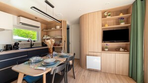 A modern kitchen with a dining area, built-in shelves, and a flat-screen TV.