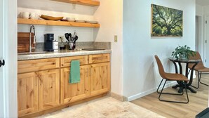 Una cocina moderna con armarios de madera, una cafetera y un comedor con dos sillas y una mesa.