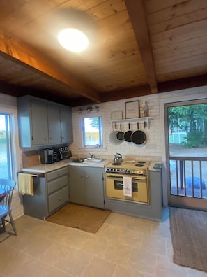 A compact kitchen with a built-in oven, a sink, and a window. - Charming Great East Lake 4 Season Waterfront Home! (Acton)