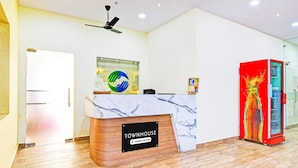 A reception desk labeled 'TOWNHOUSE' with a marble top, a ceiling fan, and a red vending machine. - Blissful Stays at Dwarakanagar Near Gurudwara (Visakhapatnam)