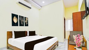 A hotel room with a bed, a desk, a chair, and a wall-mounted air conditioner. - Blissful Stays at Dwarakanagar Near Gurudwara (Visakhapatnam)