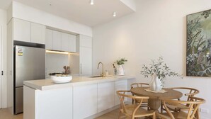 A modern kitchen with white cabinetry, a central island, and a dining area with wooden chairs.