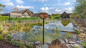 Un étang avec un panneau en bois, des bâtiments en bois et une clôture en bois.