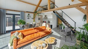 Un vaste espace de vie comprenant un canapé, une table basse et un escalier menant à un niveau supérieur.