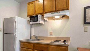 A compact kitchen with wooden cabinets, a white refrigerator, a microwave, and a gas stove. - 2 Full Beds | Non-Smoking, Kitchen (Bossier City)