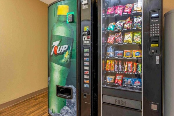 A 7UP vending machine and a snack vending machine with various snacks.