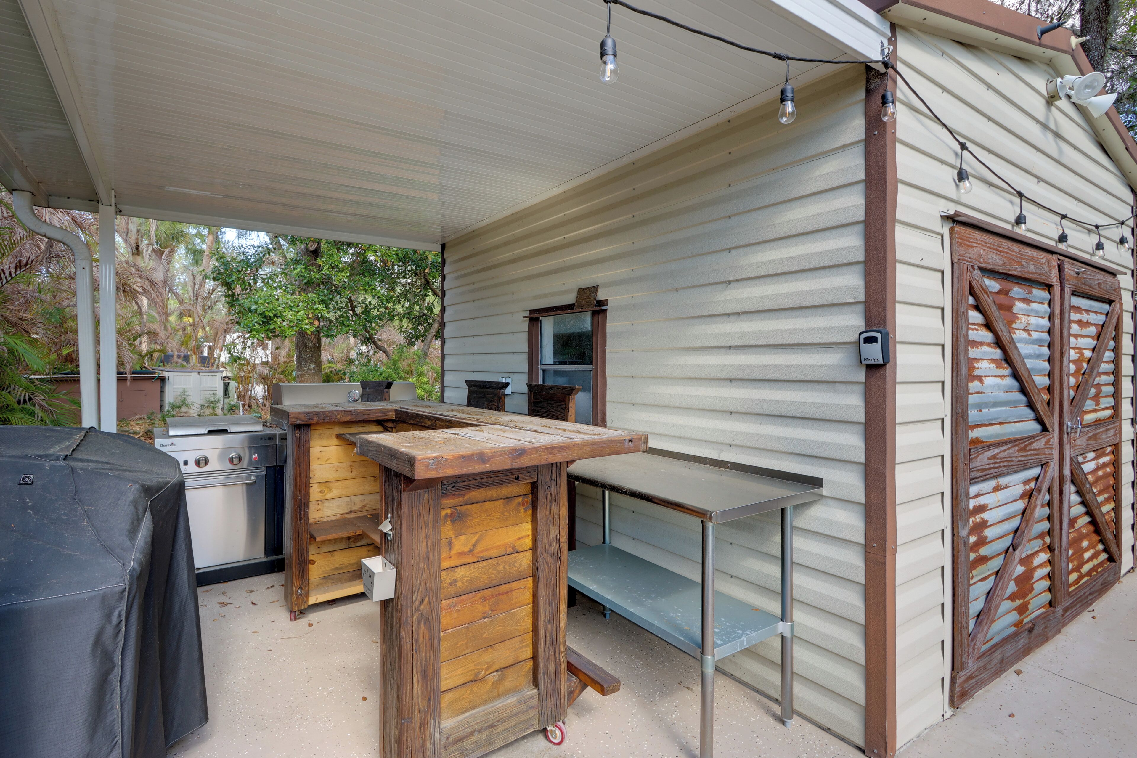 Un espace cuisine extérieur comprenant un barbecue, une table en bois et une table en métal.