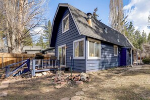 Ein zweistöckiges Haus mit einem steilen Satteldach, einer Veranda mit blauer Brüstung und einer Holzterrasse.