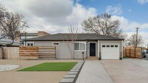 Ein modernes, zweistöckiges Haus mit Garage, Vorgarten mit Rasen und Kiesweg sowie Holzzaun.