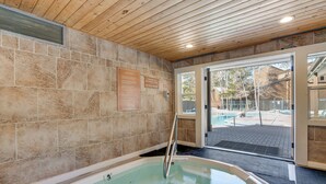 A spa area with a hot tub, wooden ceiling, stone walls, and a view of the outdoor pool area. - 3 Mi to Keystone Resort: Updated Condo w/ Balcony! (Keystone)
