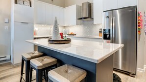 A modern kitchen with a large island, stainless steel appliances, and bar stools. - 3 Mi to Keystone Resort: Updated Condo w/ Balcony! (Keystone)