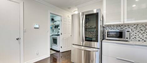 A modern kitchen with stainless steel appliances, white cabinetry, and a patterned backsplash.