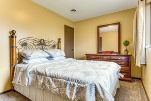 A bedroom with a bed, dresser, mirror, and a door. - Rural Bloomington Area Home w/ Deck & Yard! (Bloomington)