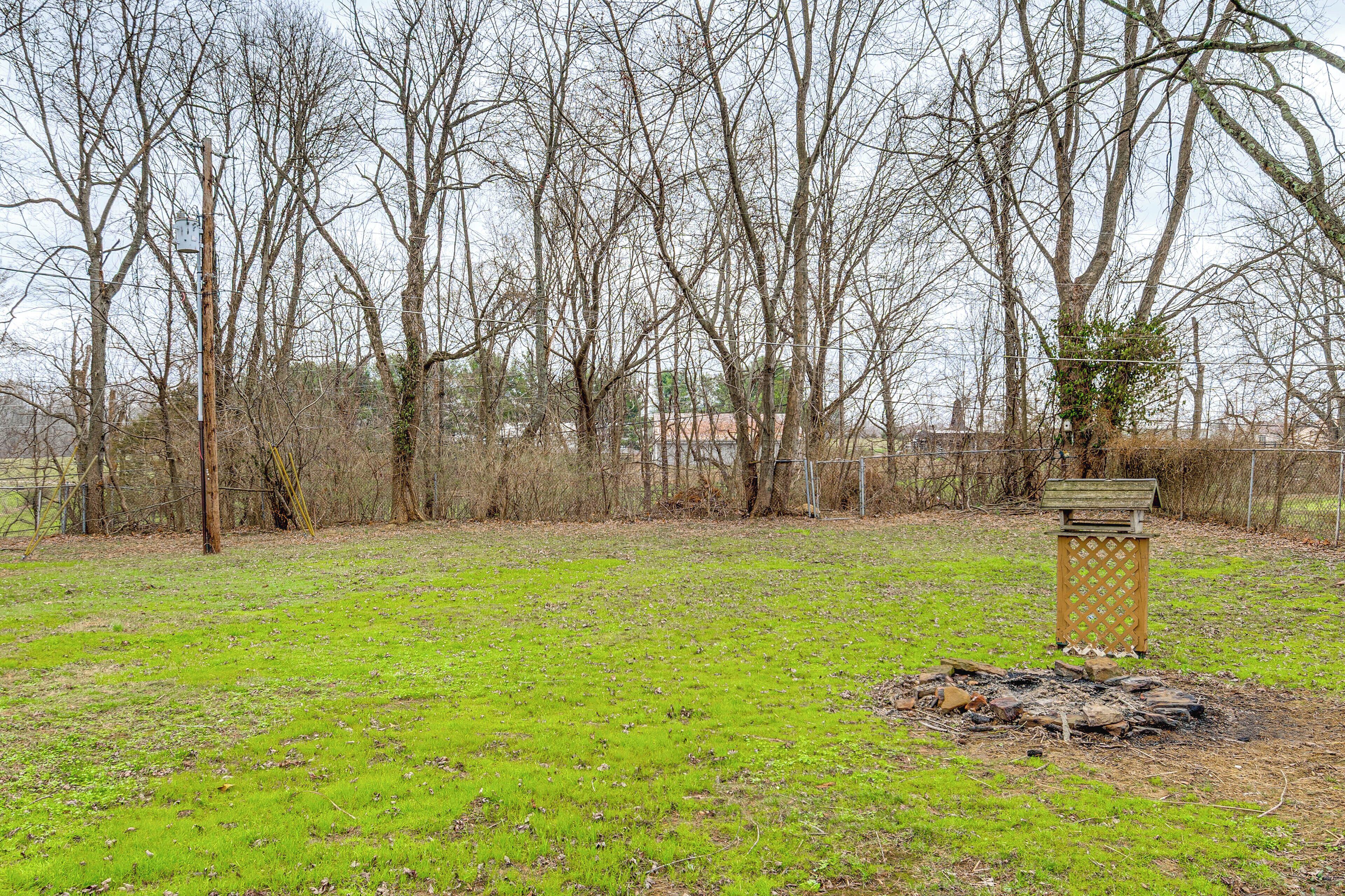 Un champ herbeux avec une structure en bois et une clôture métallique en arrière-plan.